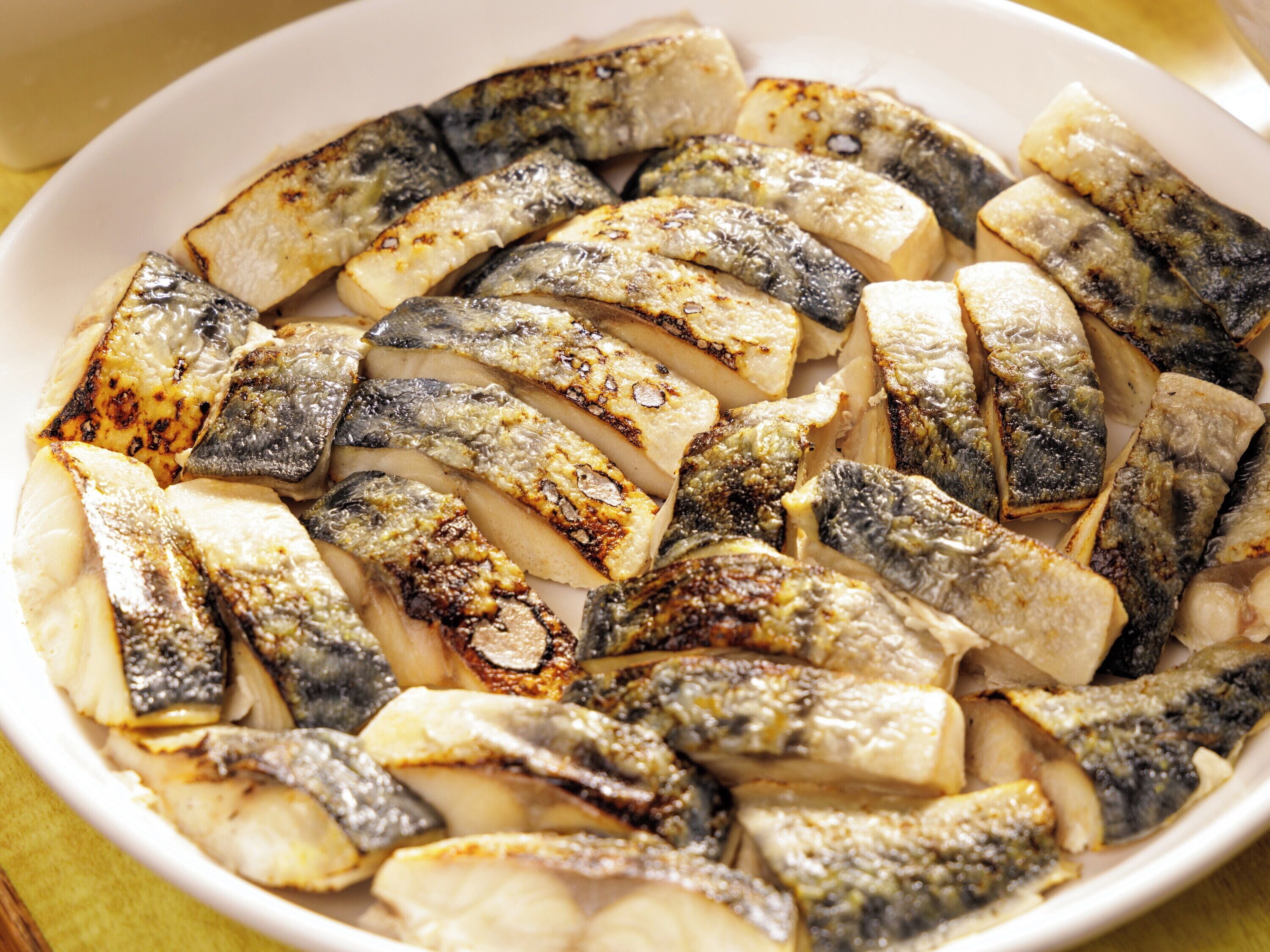 A white plate with grilled fish and potatoes.