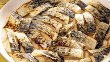 A white plate with grilled fish and potatoes.