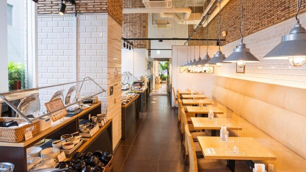 Un restaurante con paredes de ladrillo, mesas de madera y lámparas colgantes.
