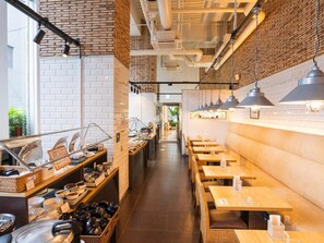 A restaurant with brick walls, wooden tables, and hanging pendant lights.