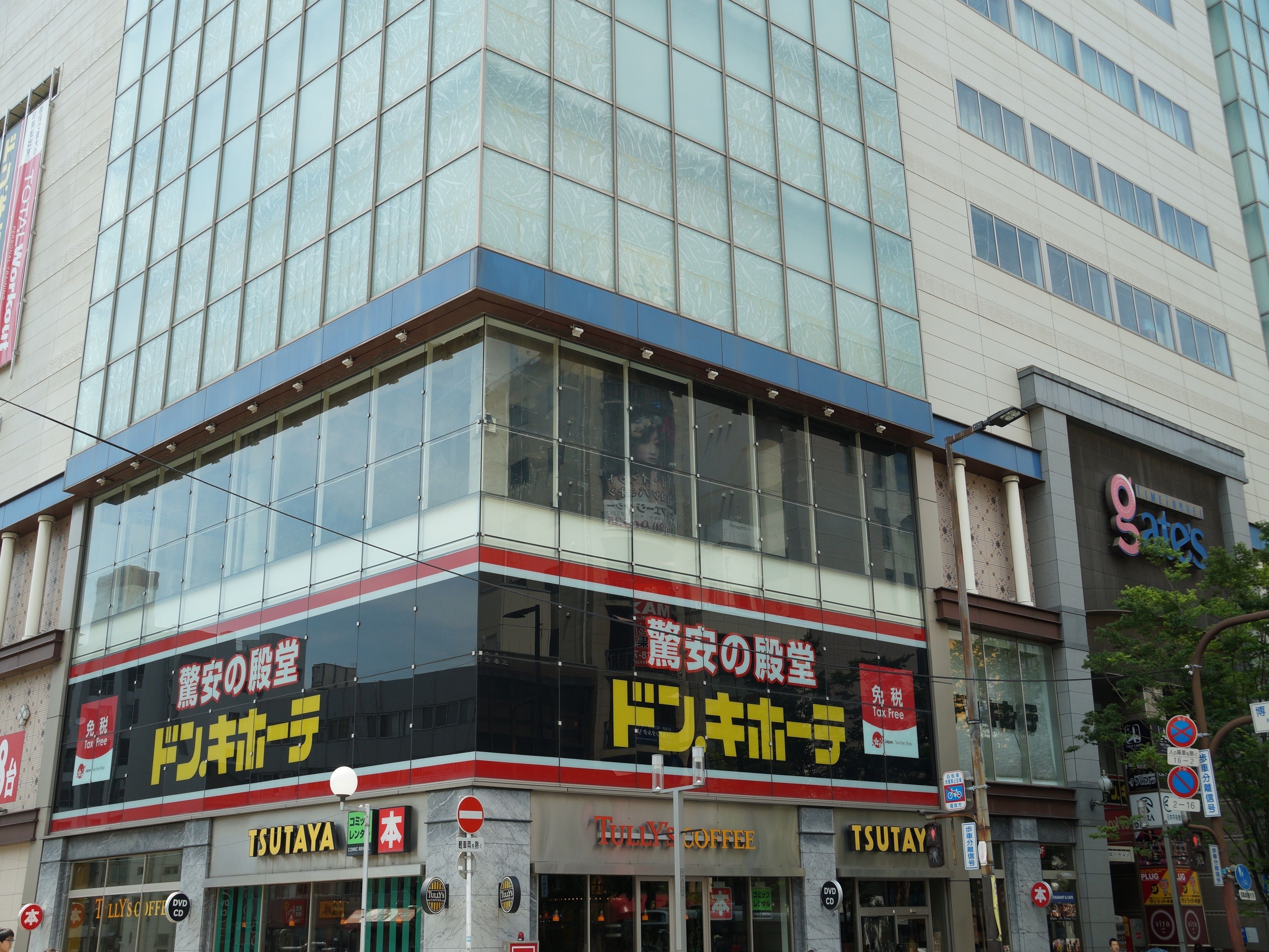 A building with multiple storefronts, including a coffee shop and a store with a prominent sign in a foreign language.