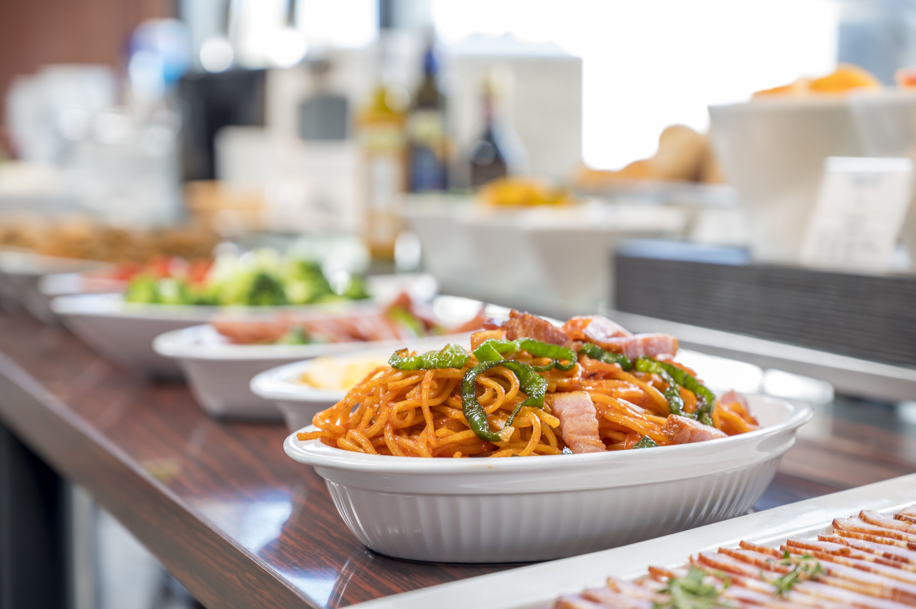 A buffet with various dishes including noodles, vegetables, and meats.