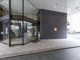 Entrada moderna de un hotel con puerta de vidrio, pantalla digital y un cartel que indica el nombre 'Nishitetsu Inn'.