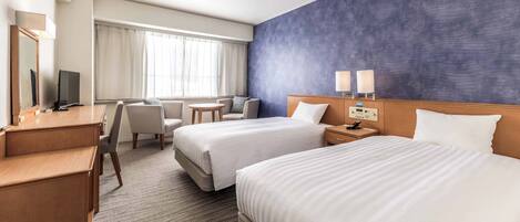 Une chambre d’hôtel avec deux lits, un bureau, une chaise, une petite table et un téléviseur.