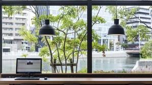 A modern workspace with a desk, computer, and two chairs, overlooking a river and cityscape. - Nishitetsu Inn Fukuoka (Fukuoka)