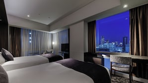 A hotel room with two beds, a desk, a chair, and a large window with a city view. - Solaria Nishitetsu Hotel Ginza (Tokyo)