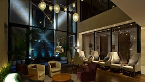 A modern lobby with a curved seating area, a coffee table, and a large window with blinds. - Solaria Nishitetsu Hotel Ginza (Tokyo)