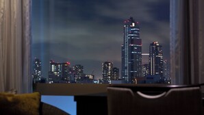 A cityscape view from a window with curtains, featuring tall buildings and a clear sky. - Solaria Nishitetsu Hotel Ginza (Tokyo)