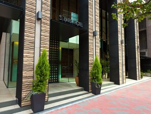 L’extérieur de l’hôtel Solaria se distingue par sa façade moderne, son grand hall d’entrée vitré et les plantes en pot qui l’ornent.