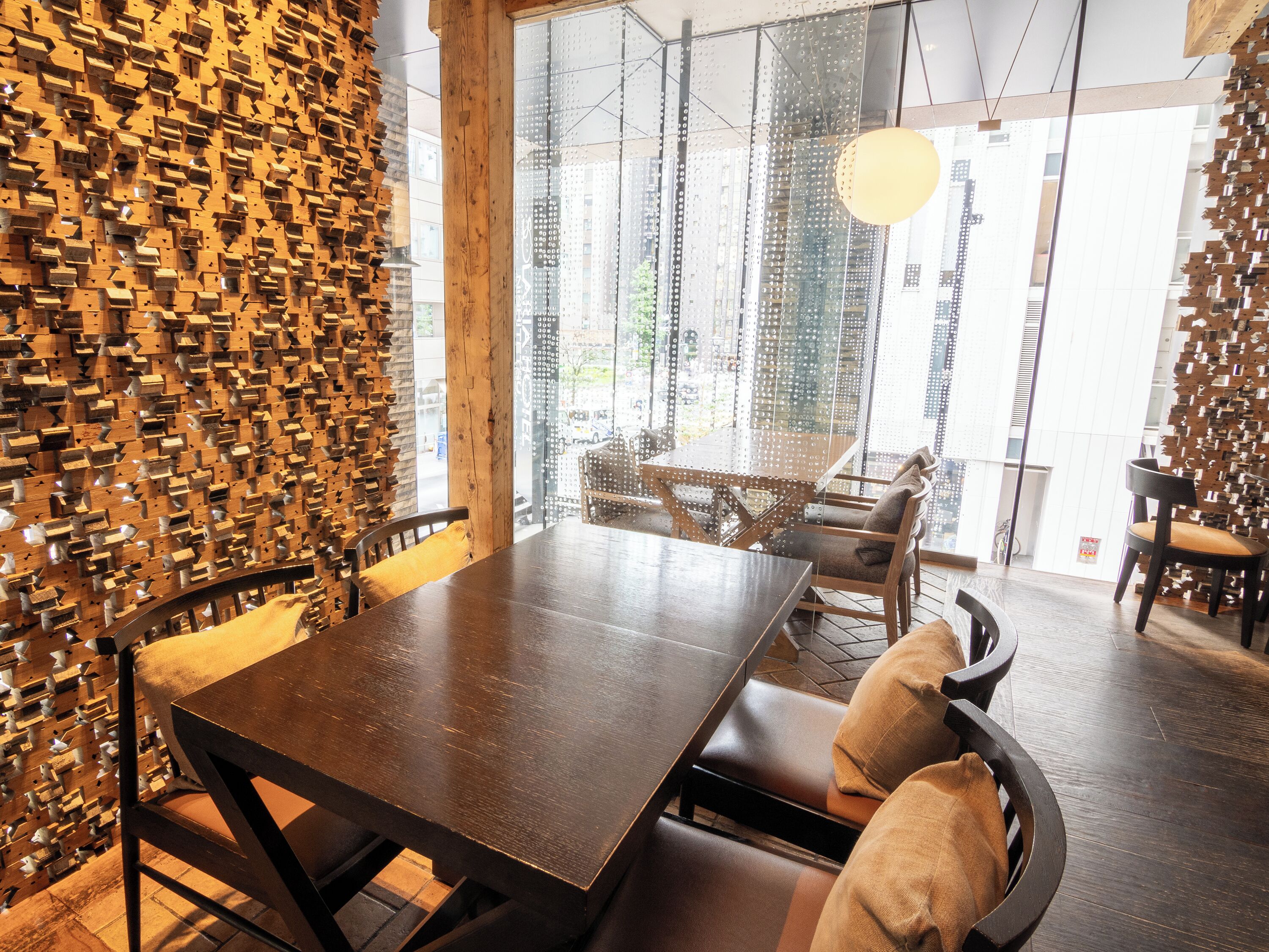 A modern dining area with a wooden wall, a large table, and chairs.