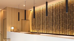 Un espace d’accueil moderne avec un mur revêtu de panneaux en bois, un comptoir d’accueil blanc et deux tabourets minimalistes.