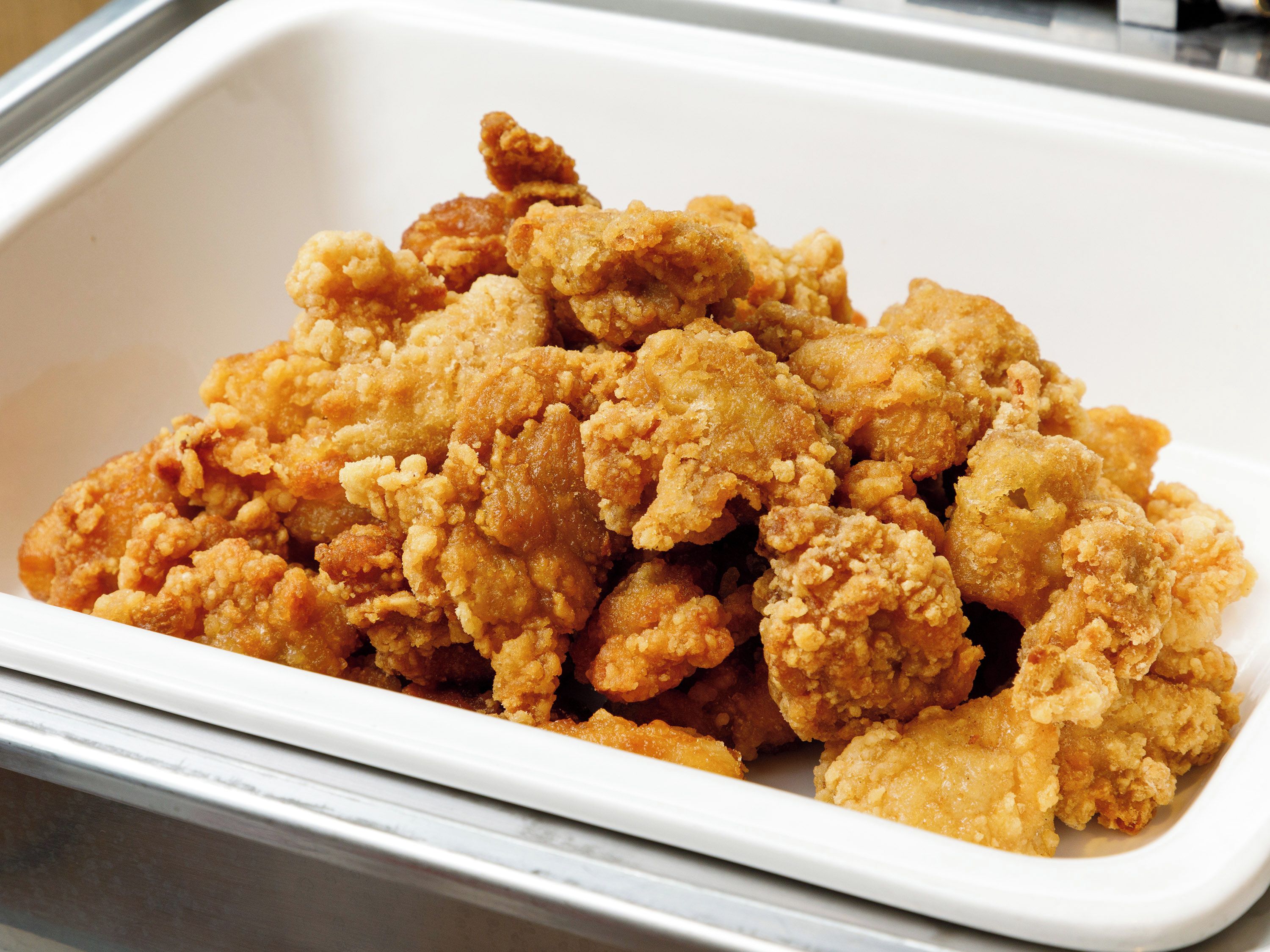 A white rectangular container filled with fried chicken pieces.