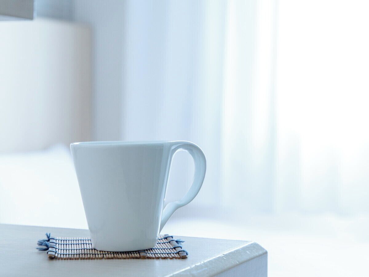 A white cup on a coaster.