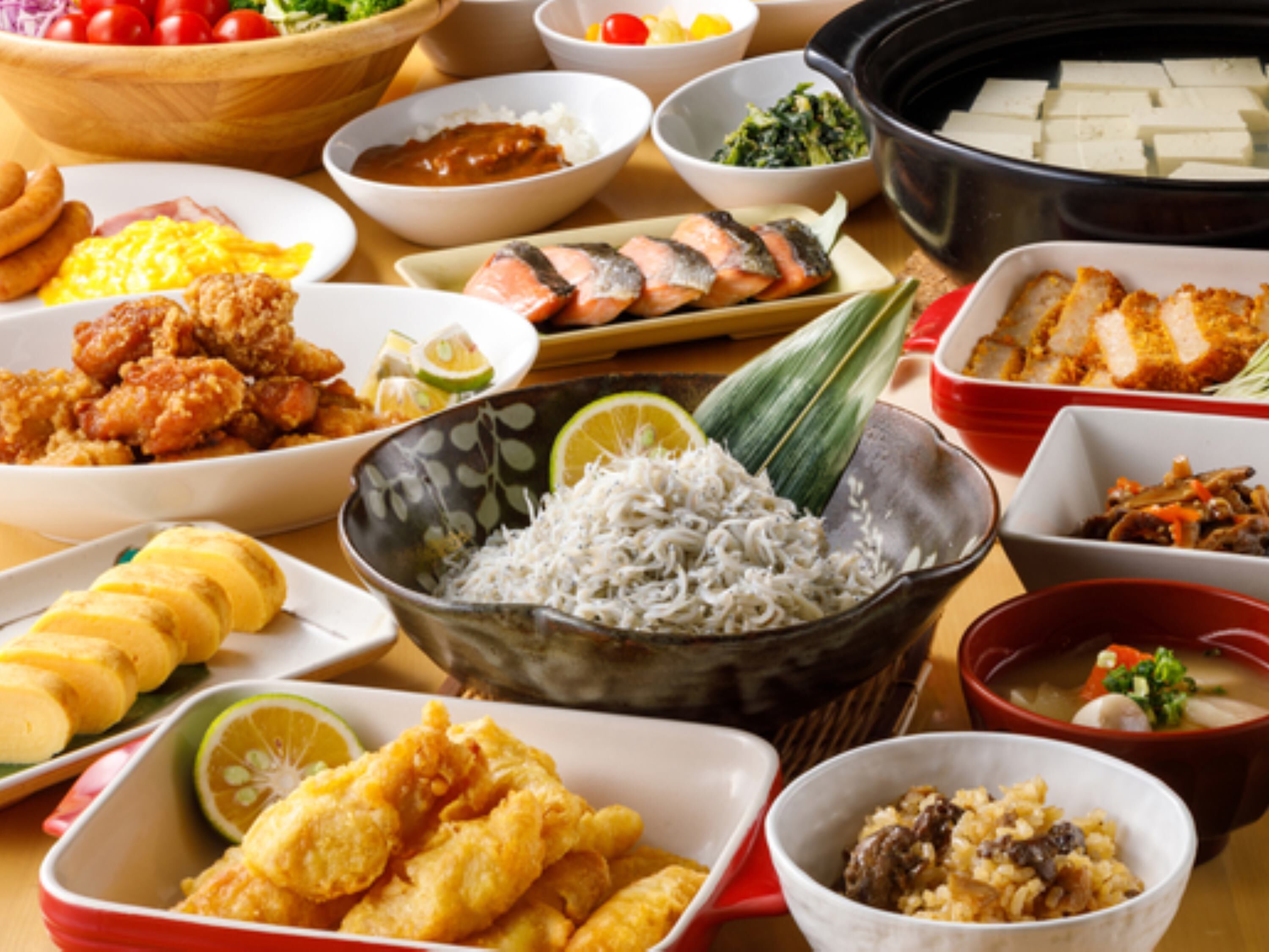 A variety of dishes including fried items, rice, and fish on a table.