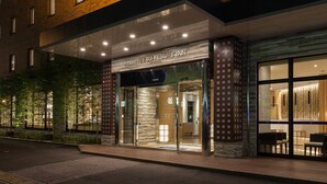 L’entrée d’un hôtel au design moderne, avec une façade en verre et une enseigne indiquant « NISHITETSU REST INN ».