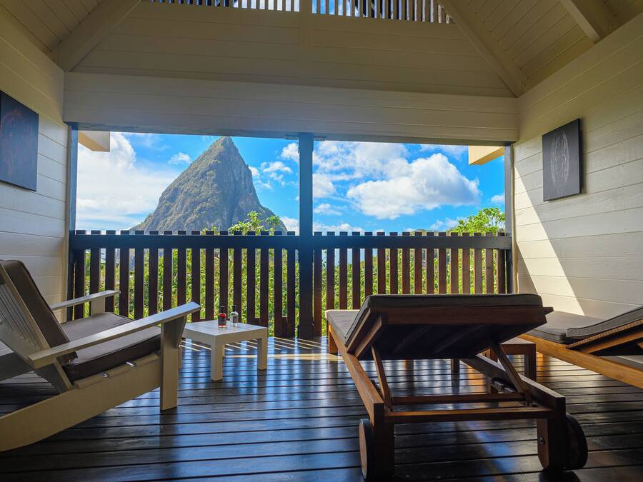 Une terrasse en bois avec des chaises longues et une table, offrant une vue sur une montagne et un ciel dégagé.