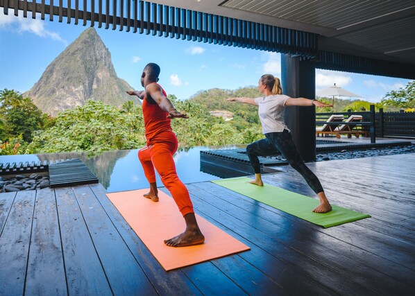 Two people practicing yoga on wooden decks with a mountain view in the background. - Rabot Hotel from Hotel Chocolat (Soufrière)