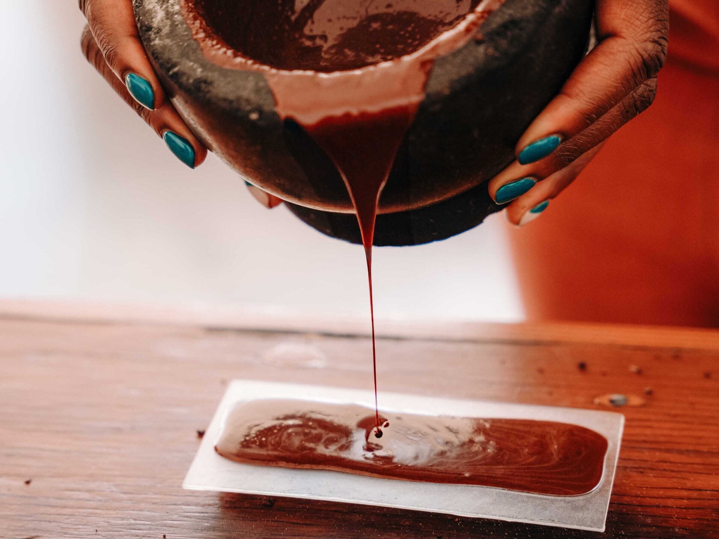 Alguém despeja chocolate de uma tigela sobre uma superfície branca.