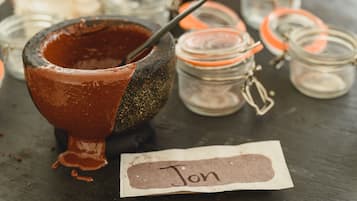 Un décor rustique avec un bol en pierre contenant un liquide brun, entouré de petits pots en verre dotés de couvercles en métal.