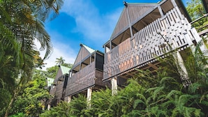 A row of wooden buildings with balconies, surrounded by lush greenery and ferns. - Rabot Hotel from Hotel Chocolat (Soufrière)
