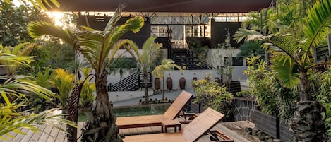 A wooden deck with lounge chairs, a stone wall, and a view of a mountain.
