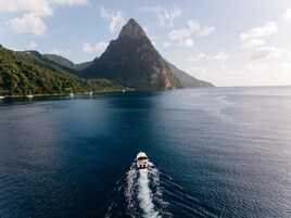 Um barco desliza por um mar calmo, com uma ilha montanhosa ao fundo.