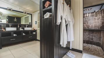 A modern bathroom with a black vanity, two sinks, a large mirror, and a stone wall feature.