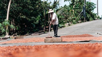 A person working with red material on a road, surrounded by greenery.