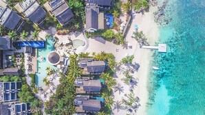 An aerial view of a resort with multiple overwater bungalows, a central pool area, and a beach with clear turquoise waters. - Le Jadis Beach Resort & Wellness - Managed by Banyan Tree Hotels & Resorts (Balaclava)