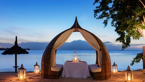 Un espace de restauration aménagé sur la plage, avec un auvent, une table, des chaises et des lanternes.
