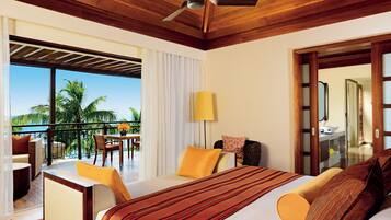 A hotel room with a large bed, a balcony with a table and chairs, and a view of palm trees.