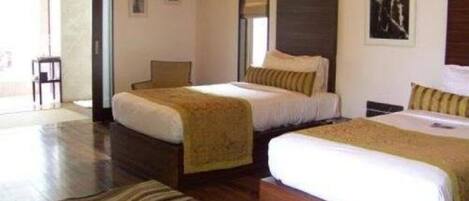 A hotel room with two beds, a chair, and a large window.