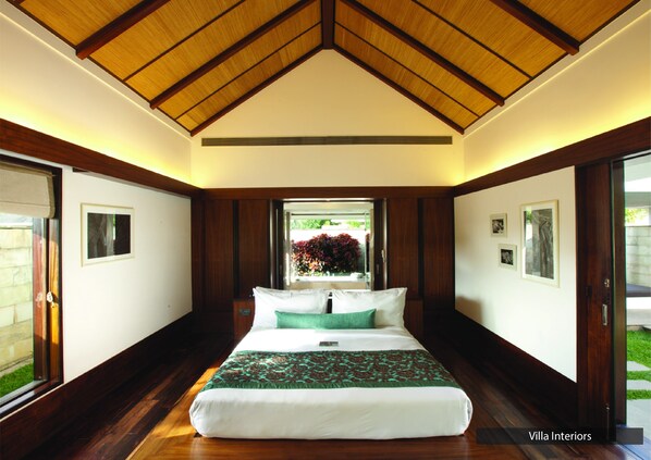 Un dormitorio con una cama grande, techo de madera y vistas a un jardín a través de una ventana.