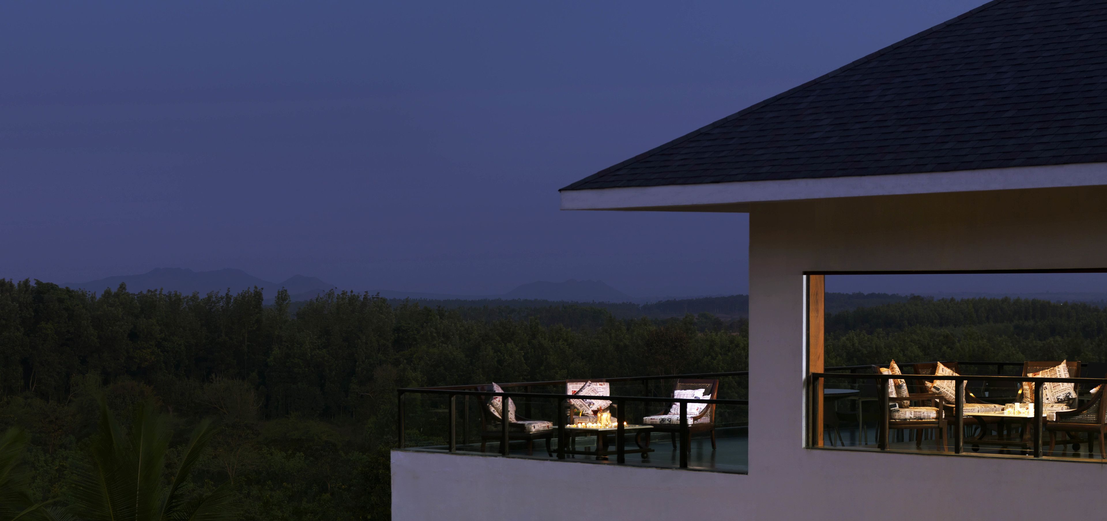 A modern building with a balcony overlooking a forested landscape.