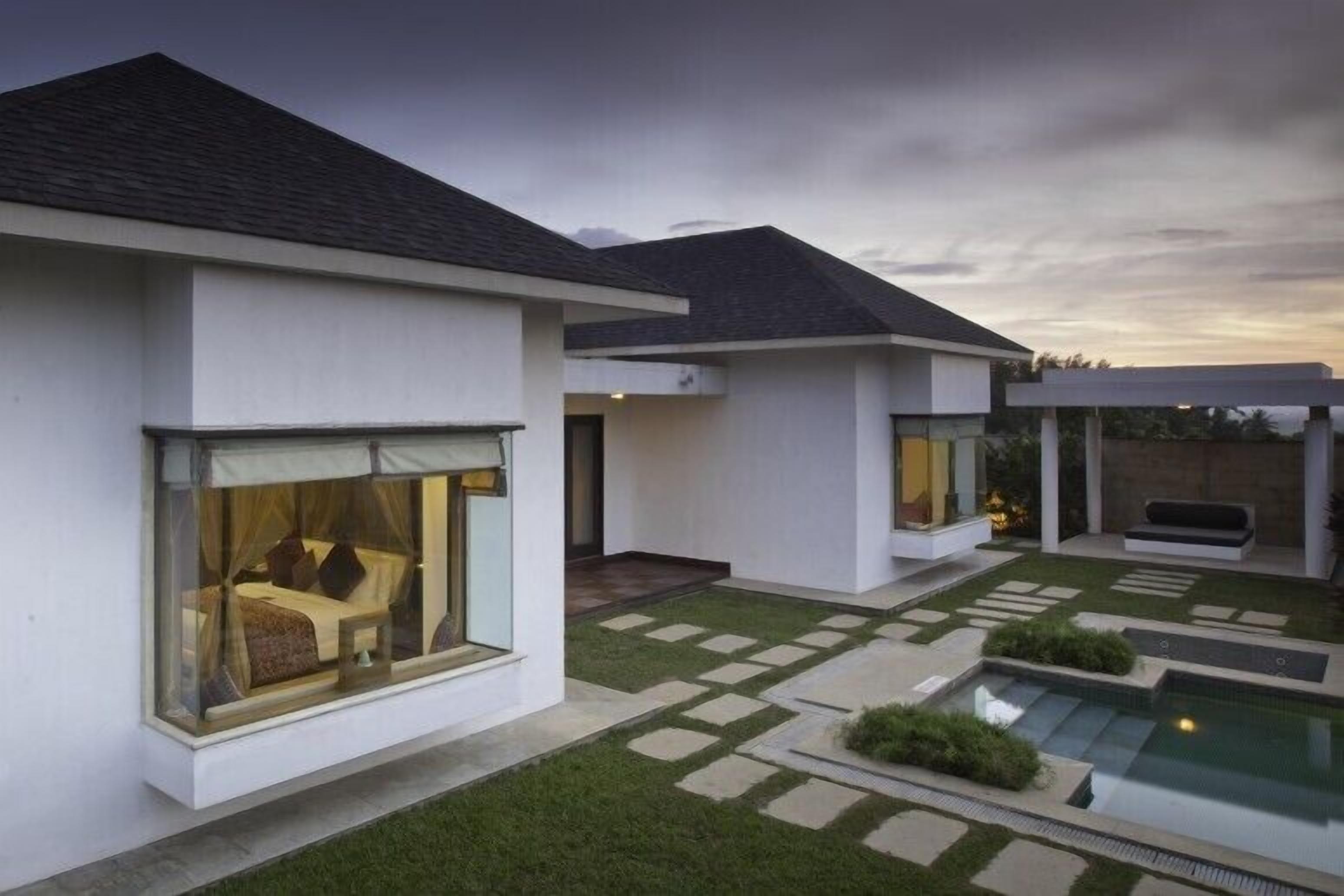 A modern house with a swimming pool, a covered patio, and a well-maintained lawn.