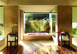 Un baño moderno con un ventanal grande, suelo de madera y vistas a espacios verdes.