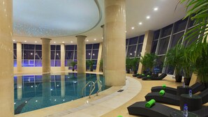 An indoor swimming pool with lounge chairs and potted plants. - Radisson Hotel Tianjin Aqua City (Tianjin)