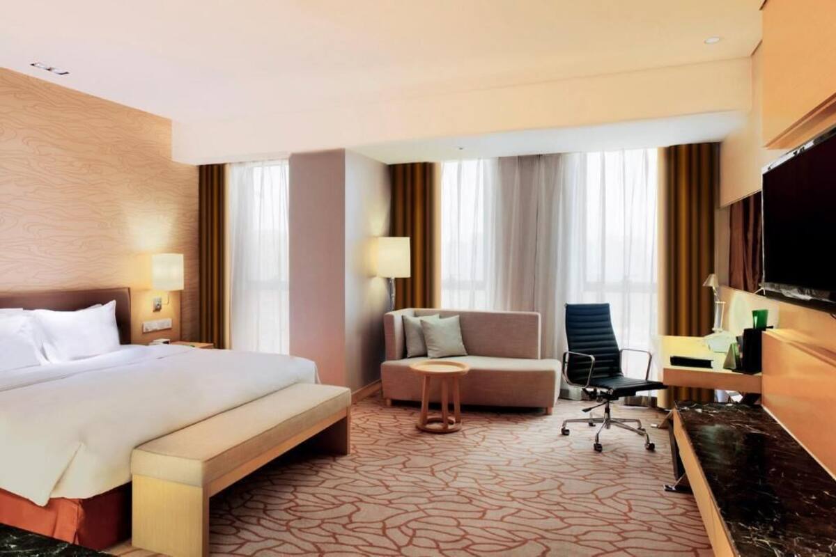 A hotel room with a bed, a sofa, a desk, and a TV.
