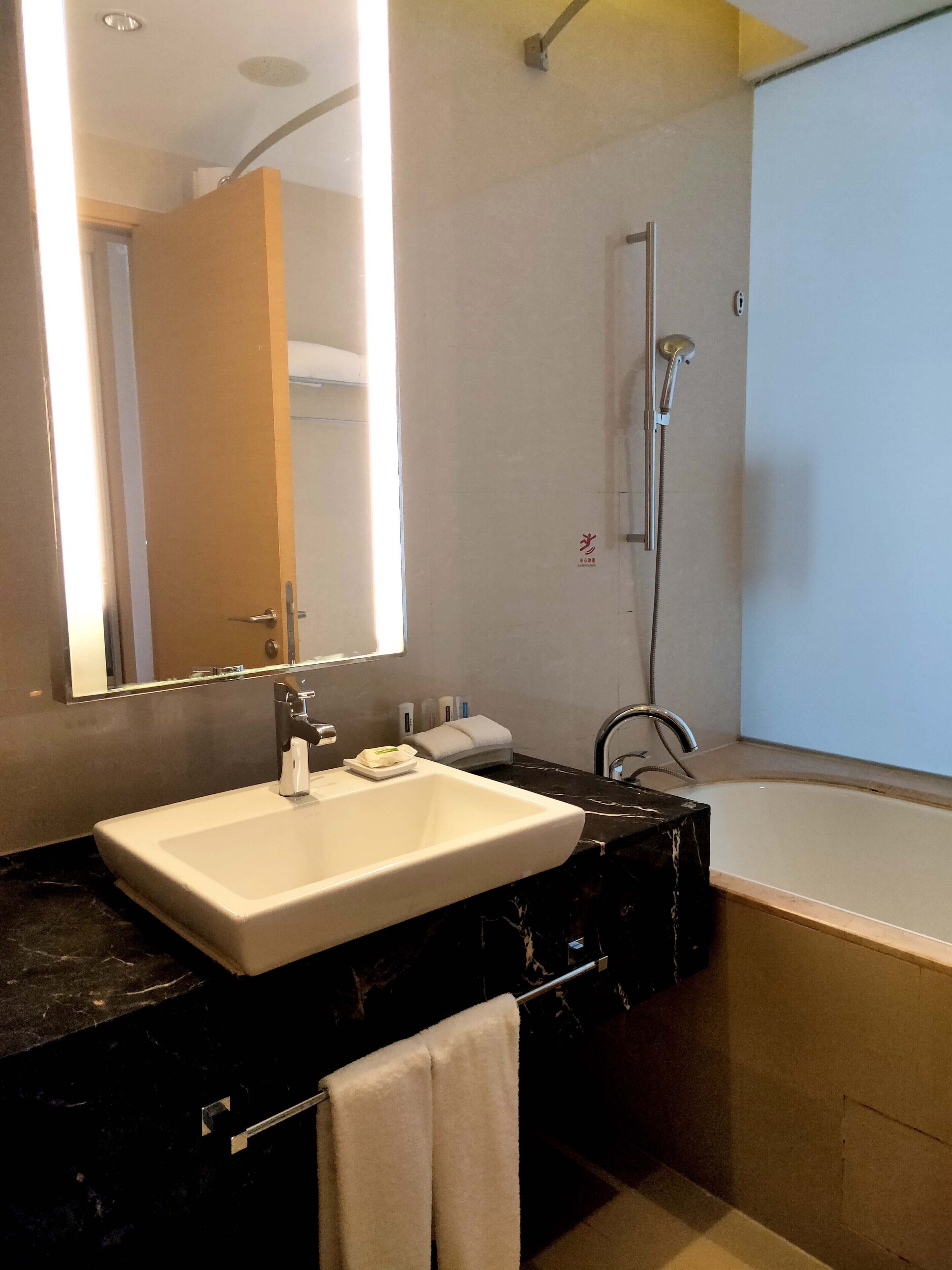 A modern bathroom with a large mirror, a sink, a shower, and a bathtub.