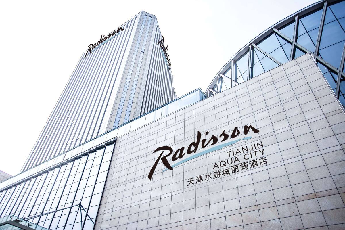 A Radisson hotel with a modern glass facade and signage indicating it is located in Tianjin, China.