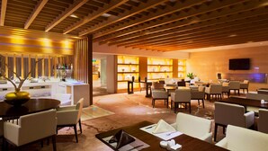 A modern hotel lobby with a wooden ceiling, a bar area, and a seating area with tables and chairs. - Radisson Hotel Tianjin Aqua City (Tianjin)