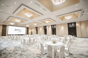 A conference room with round tables, white chairs, and chandeliers. - Radisson Hotel Tianjin Aqua City (Tianjin)