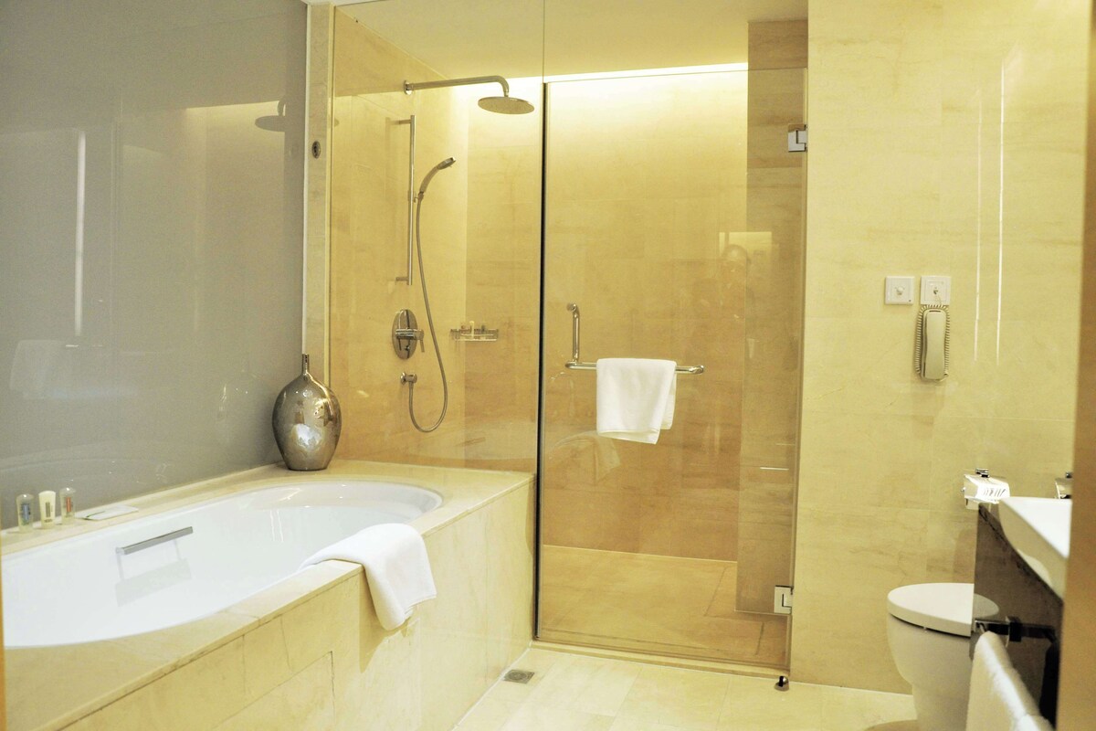 A modern bathroom with a glass-enclosed shower, a standalone bathtub, and a toilet.