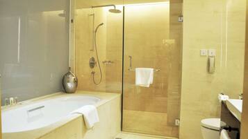 Een moderne badkamer met een glazen douchecabine, een vrijstaand bad en een toilet.