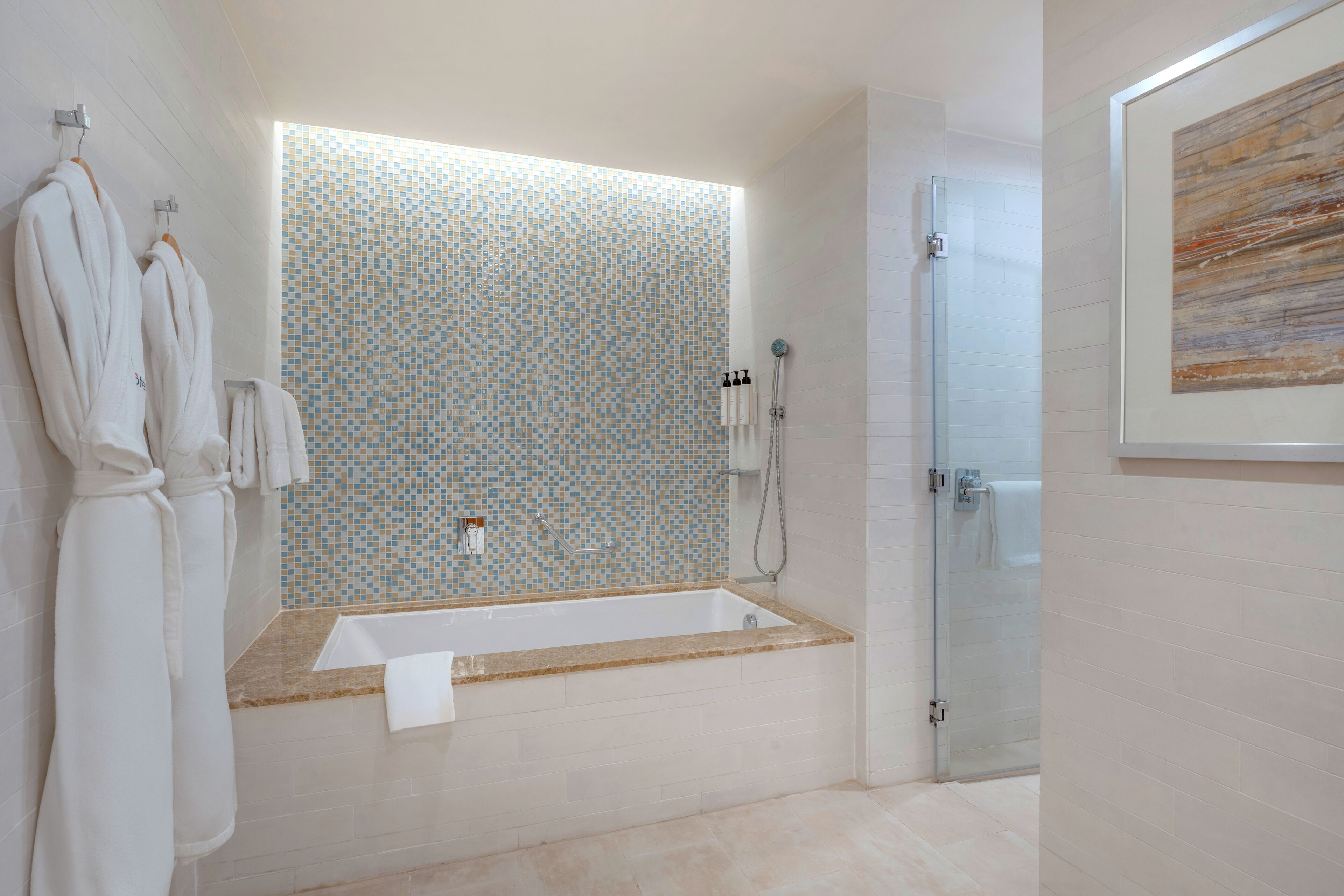 A modern bathroom with a large bathtub, a glass shower enclosure, and a tiled backsplash.