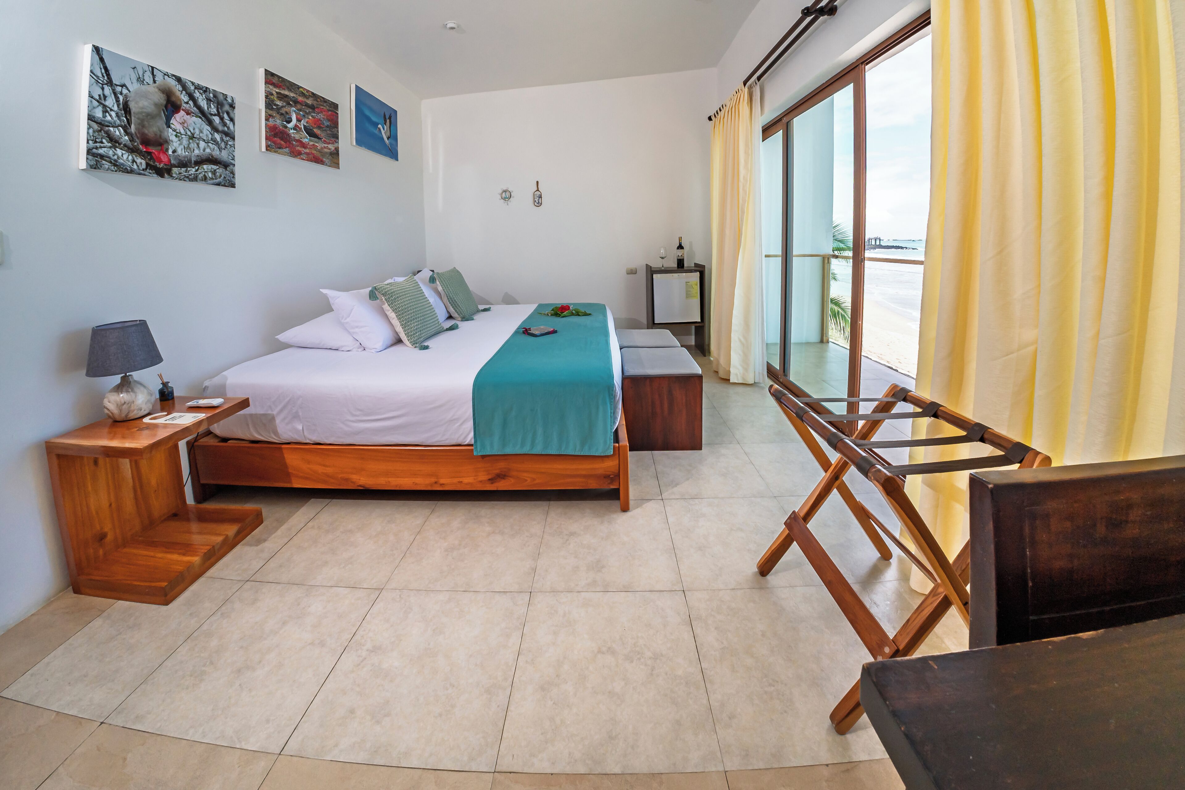 A bedroom with a bed, bedside tables, a desk, and a large window with curtains.