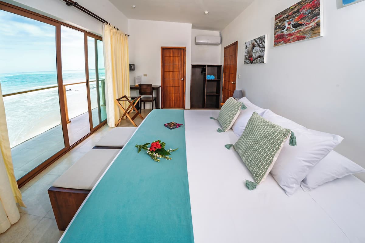 A room with a bed, a desk, and a view of the ocean.