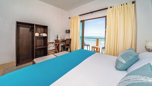 Habitación de hotel con cama, escritorio, silla, armario y vista a la playa.
