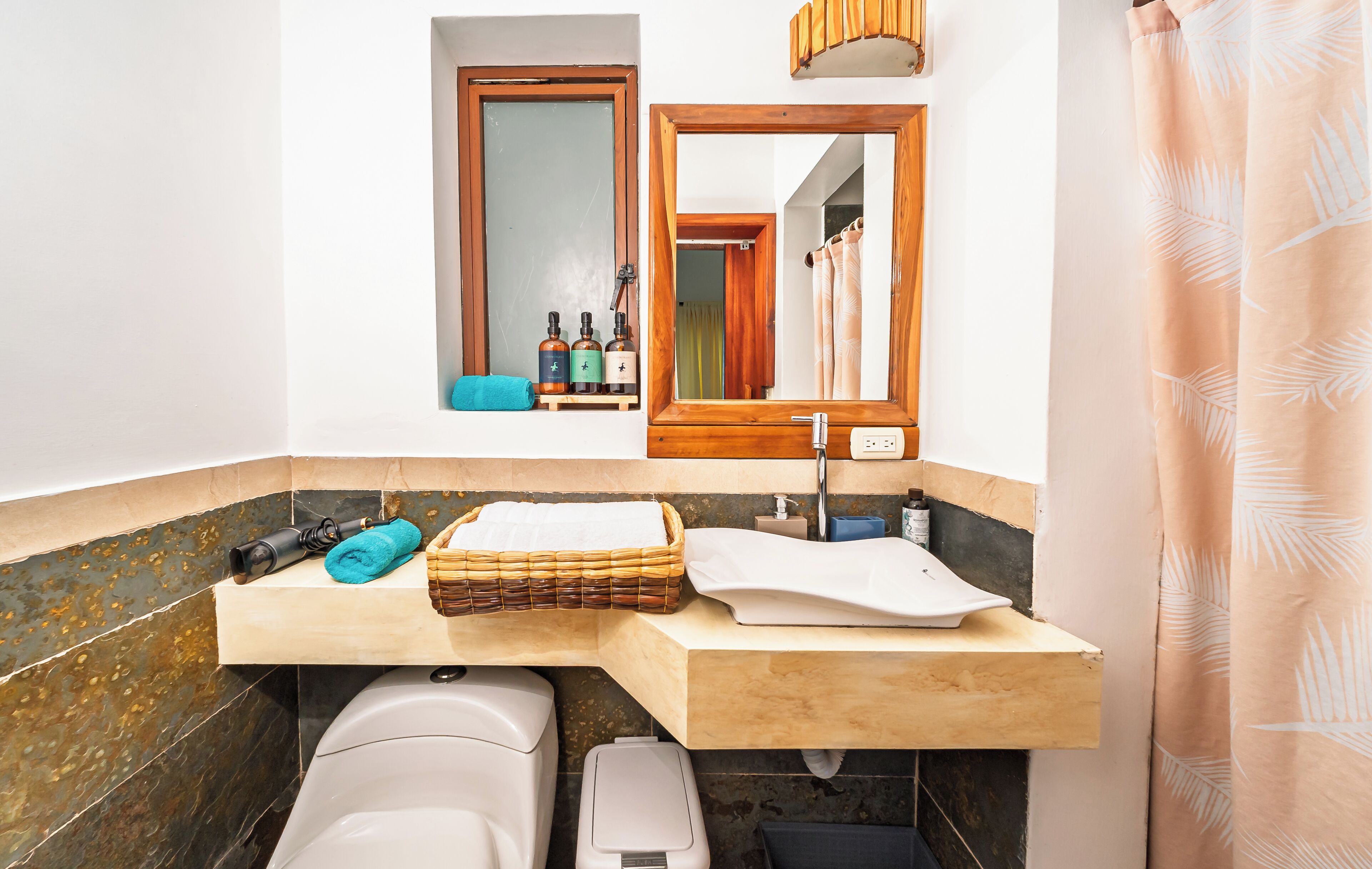 A bathroom with a wooden vanity, a mirror, a towel, and toiletries.