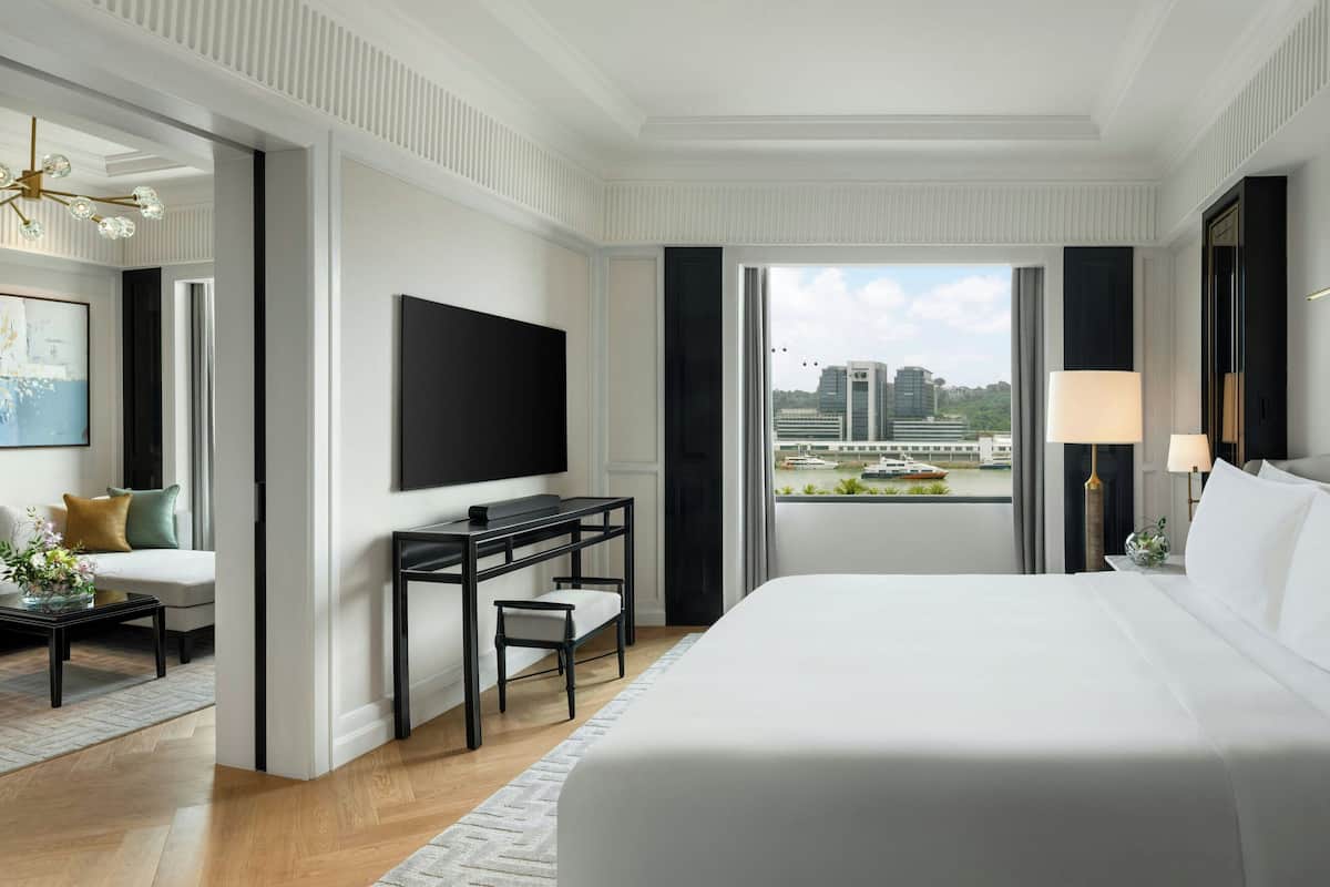 Hotelkamer met een groot bed, een bureau met stoel, een flatscreen televisie en uitzicht op de stad door het raam.